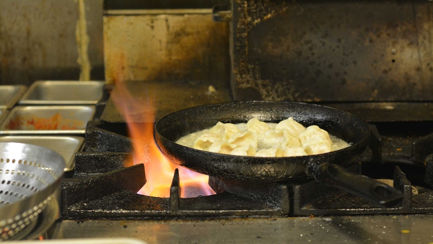 Dumplings fry in a pan over a hot flame.