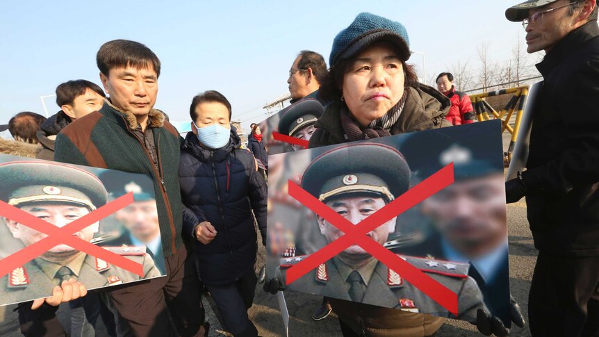 Family members of victims of the sunken South Korean naval ship Cheonan hold defaced portraits of Kim Yong Chol