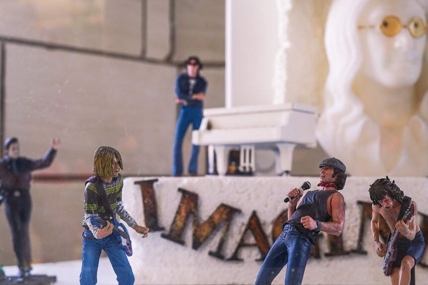 Small figurines of rock stars Kurt Cobain, John Lennon and Johnny Cash on guitars sit inside a large glass display.