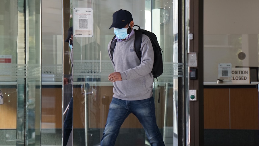 Surjeet Surjeet Kumar leaving court wearing a cap and a COVID mask.