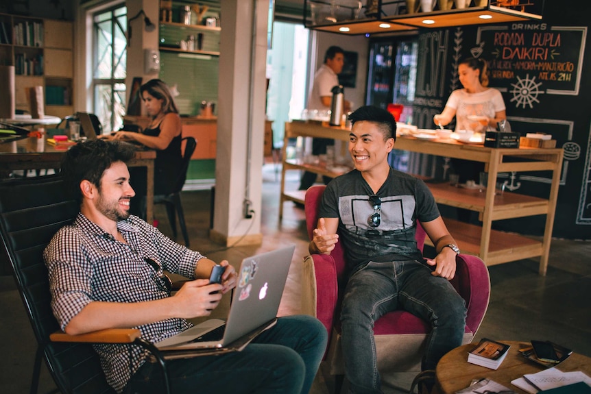 Two young men laughing and chatting in a cafe