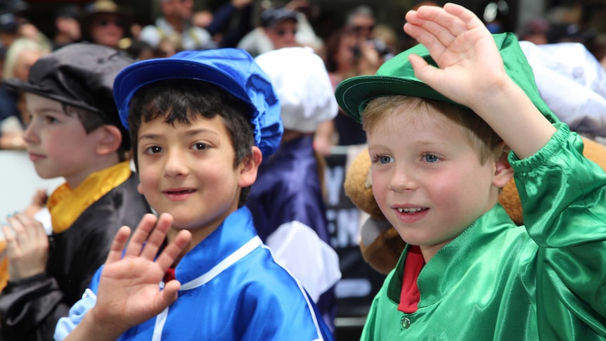 Two young boys dressed in jockey outfits enjoying the Melbourne Cup parade