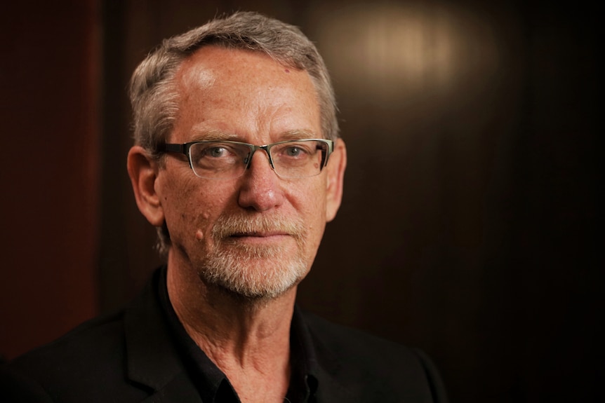 UQ Professor Paul Young wears glasses and a dark shirt and stares at the camera.