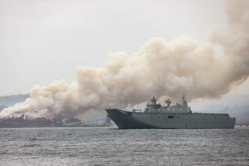 a navy ship near burning bushland