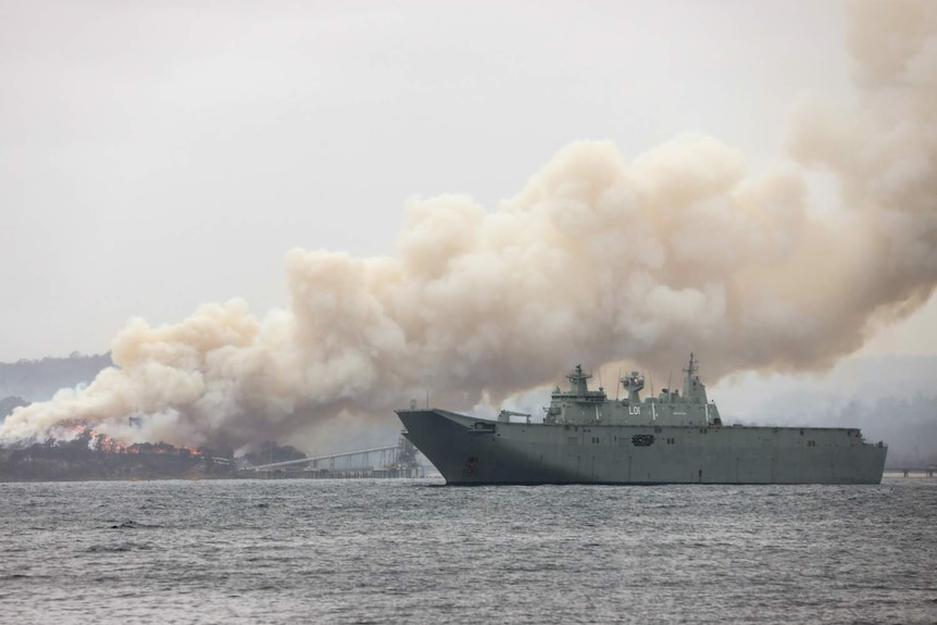 a navy ship near burning bushland