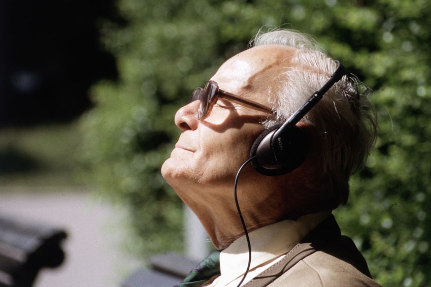 A man listens to music through headphones in the sunshine.