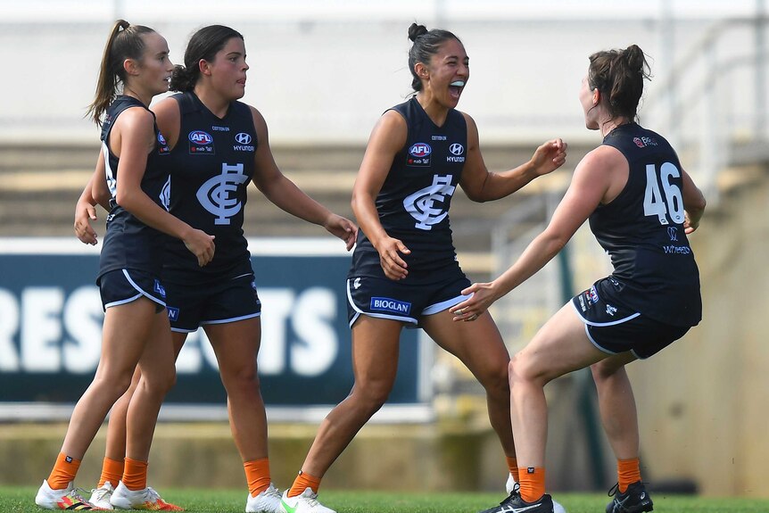 AFLW players celebrate a goal.