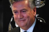 Eddie McGuire has red, teary eyes as he smirks during a press conference