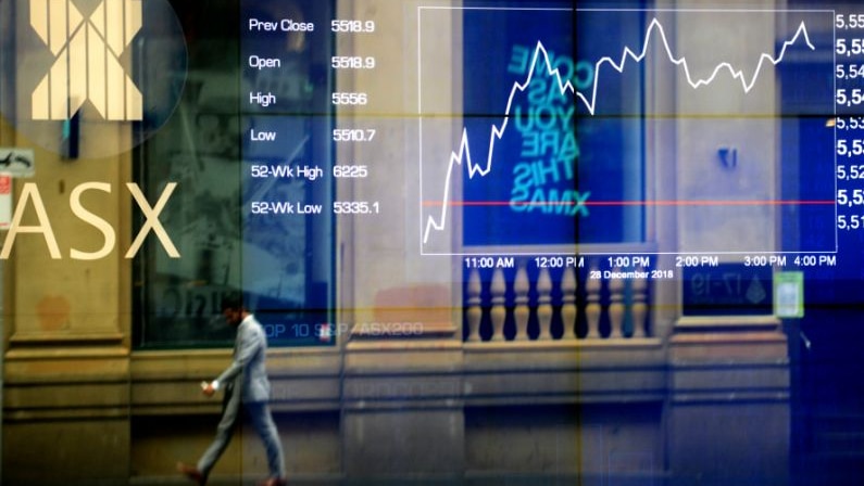 Pedestrians are seen reflected on the Australian Stock Exchange trading board in Sydney