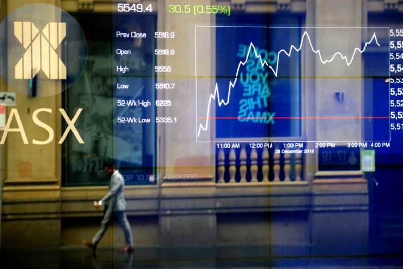 Pedestrians are seen reflected on the Australian Stock Exchange trading board in Sydney