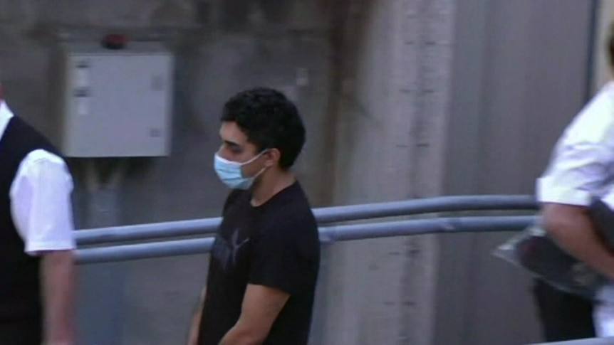 Francois Ghassibe walking handcuffed, with a face mask on 