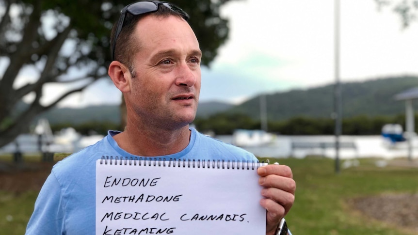 Man holding notepad with a list of the medicine he consumes to get through the day.