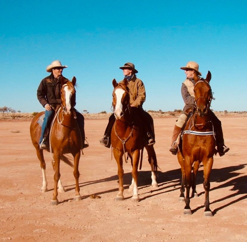 Three riders on horses in desert setting