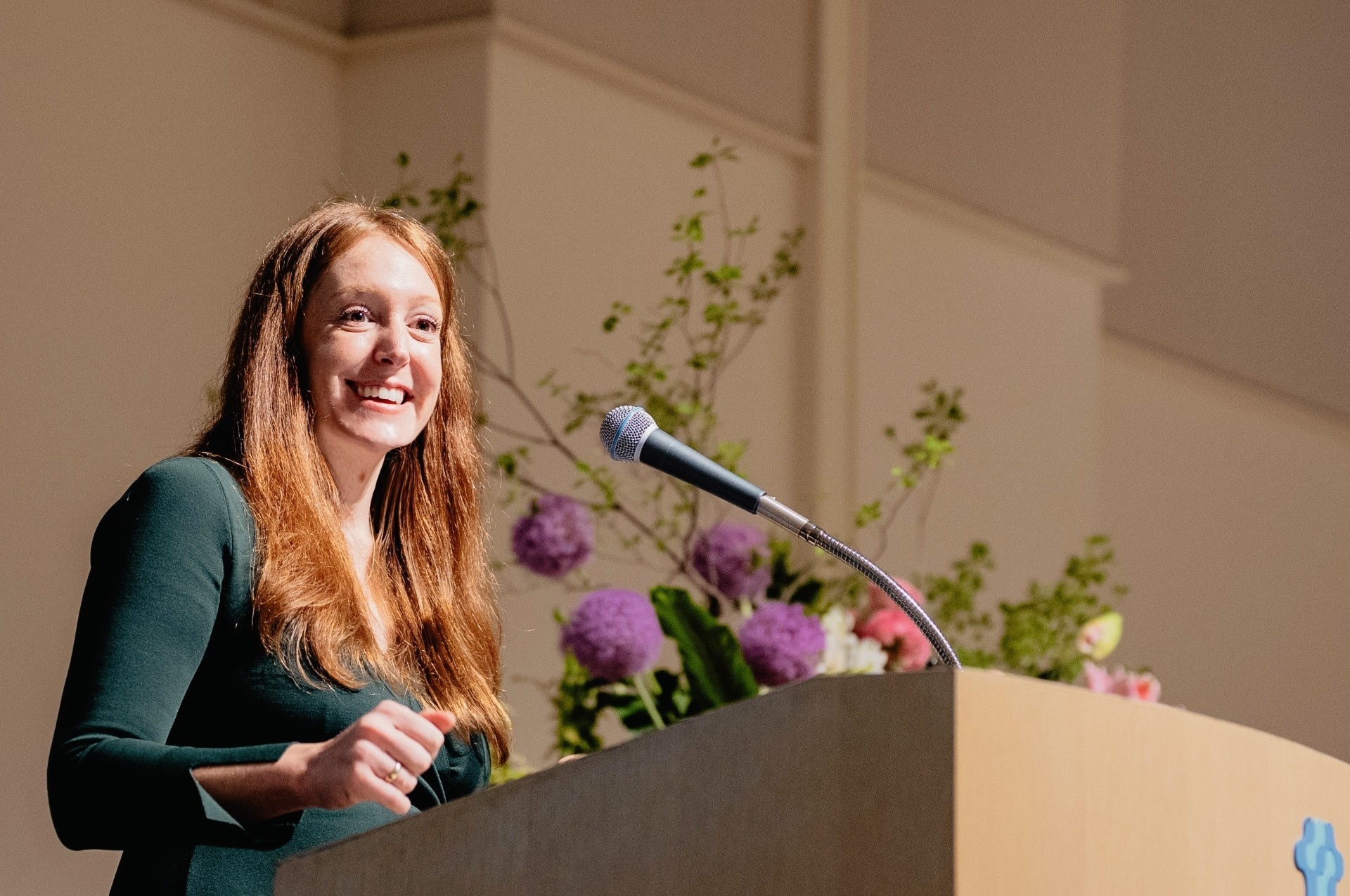 A woman stands at a lecture giving a presentation