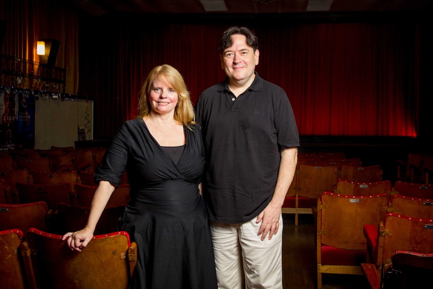 Jo Smith and George Merriman stand in the cinema aisle.