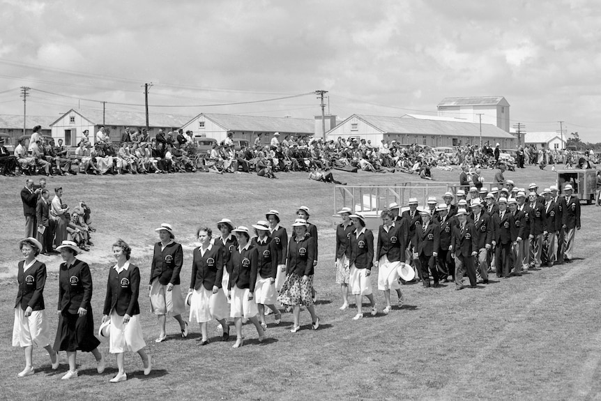 In an old photo, the England team are seen marching on a field at the 1950 Empire Games.
