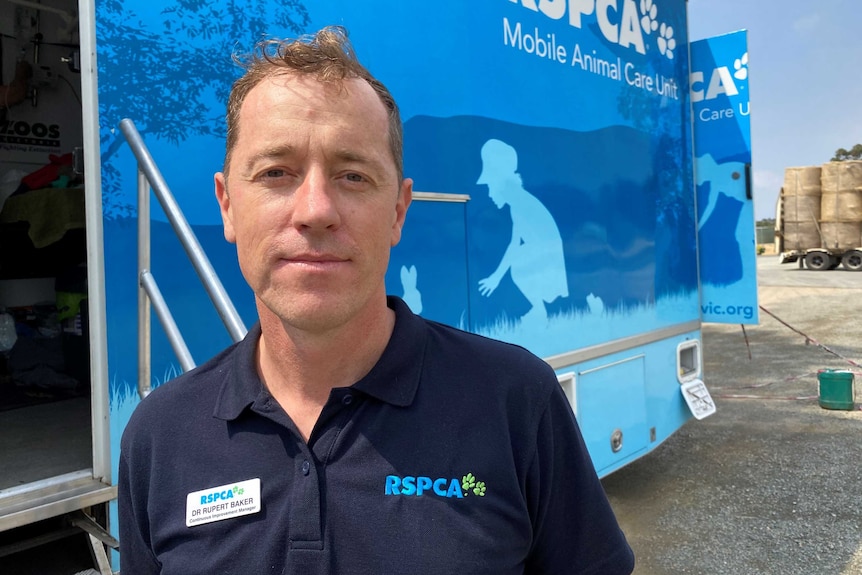 Dr Rupert Baker standing in front of RSPCA blue mobile animal care unit