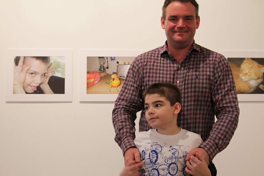 a man and child in front of photographs