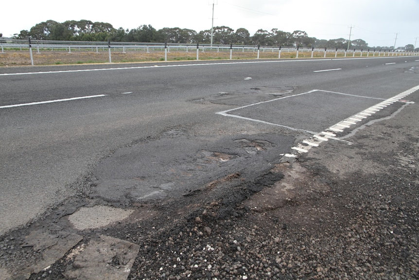 Hole in the gravel on shoulder of narrow road