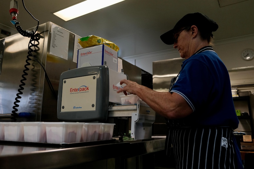 Sharon Oberhart prepares meals in a stainless steel kitchen. 