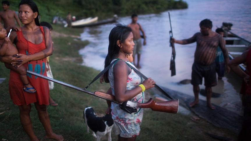 A woman holding a gun by a river