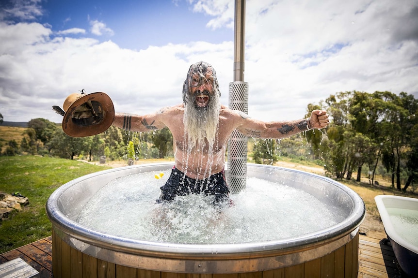 Mark takes an ice bath, holds his hat in one hand