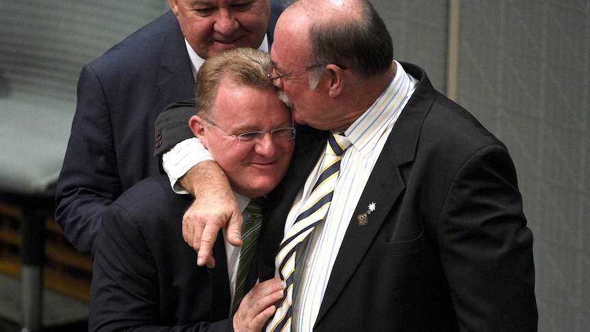 Bruce Billson is hugged by Warren Entsch in the House of Representatives on October 12, 2015
