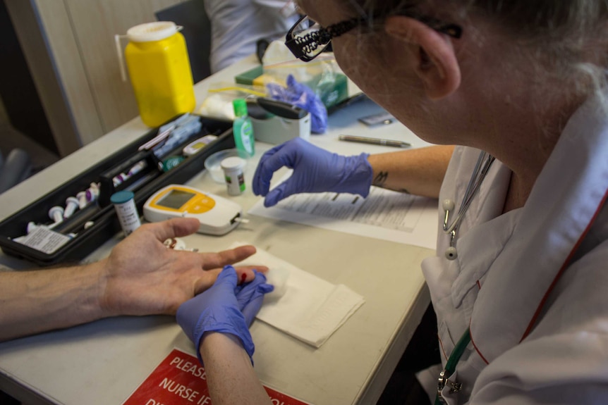 A nurse testing unidentified patient's blood sugar.