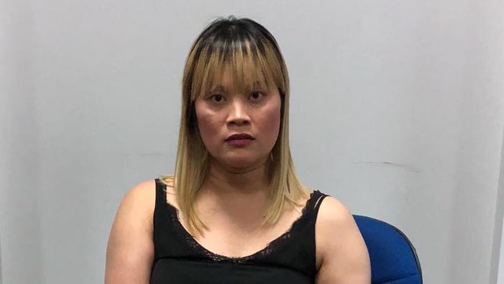 An Australian woman sits behind a stack of alleged heroin in Cambodia.