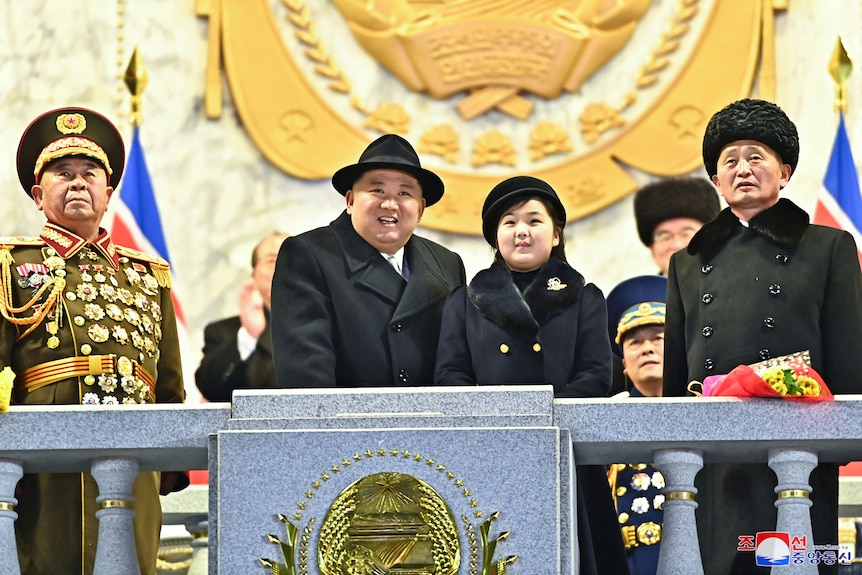 Kim Jong Un and daughter Kim Ju Ae watch a military parade from a balcony as officials stand nearby