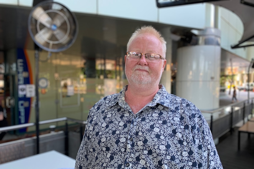 Jason Hanna is wearing a shirt with patterns and standing on the deck of a Darwin pub.