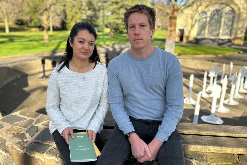 Emily and Nick Judd sit together in a park, and Emily holds a green book