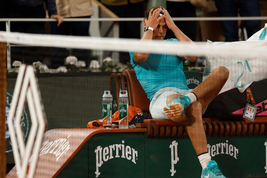 Rafael Nadal runs his hands through what's left of his hair while sitting on the side of Court Philippe Chartrier after losing.