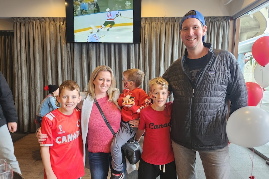 A family of three young boys, a mother and a father, smile at the camera. The boys are wearing Canada t-shirts.