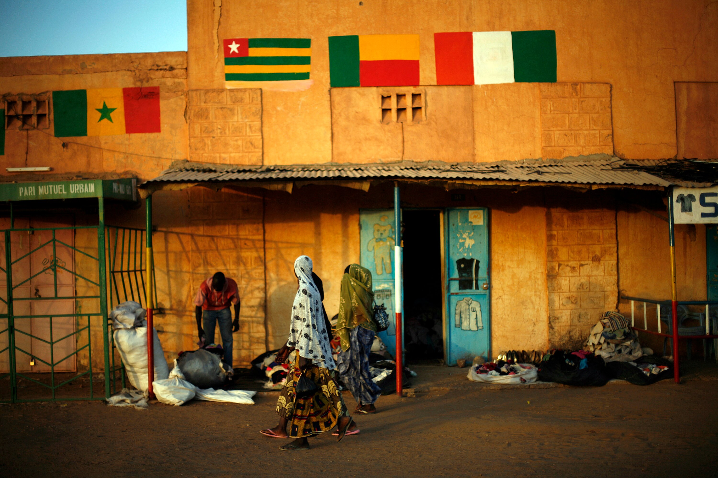 Women in hijabs walk past a brightly coloured building