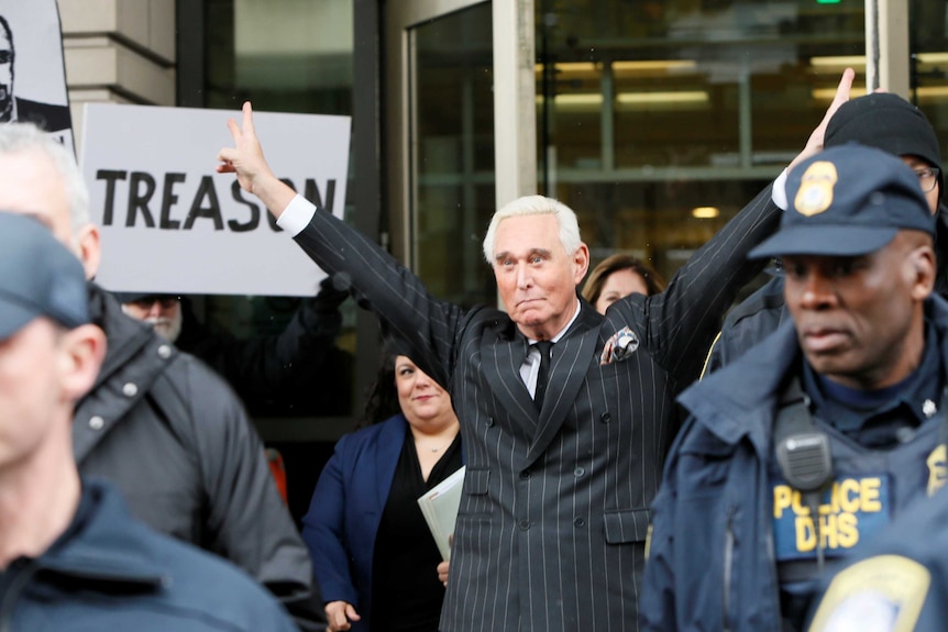 Roger Stone doing the Nixon victory peace signs surrounded by policemen