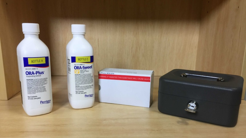 Two bottles of liquid and a box of medication are seen near a lock-box.