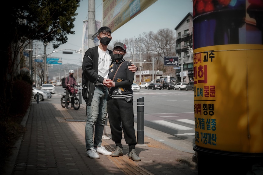 A Korean woman embraced by a tall, young man