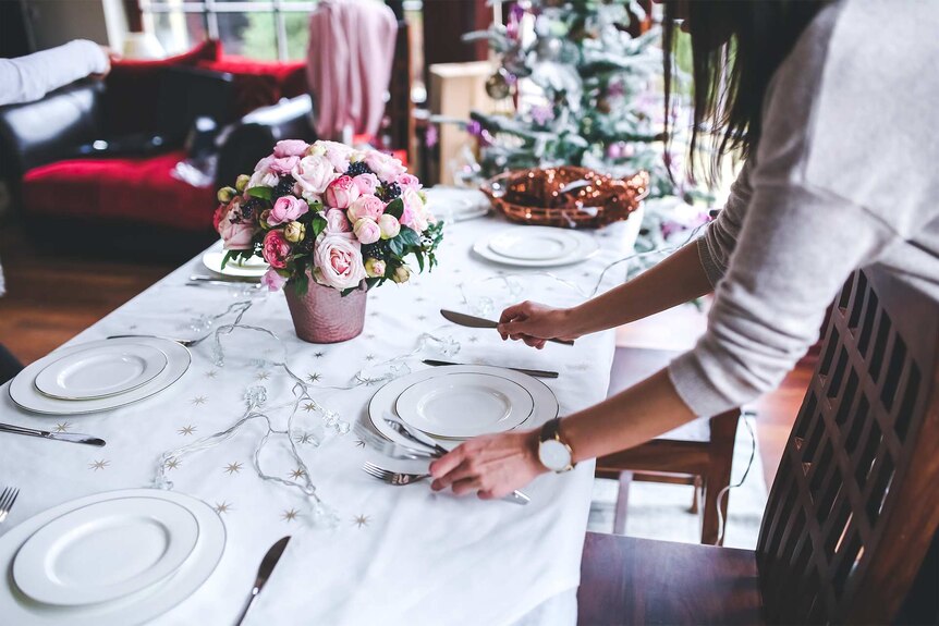 A woman setting the Christmas table to depict how to help lonely or bereaved people over Christmas.