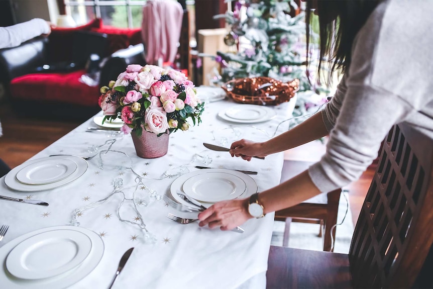 A woman setting the Christmas table to depict how to help lonely or bereaved people over Christmas.