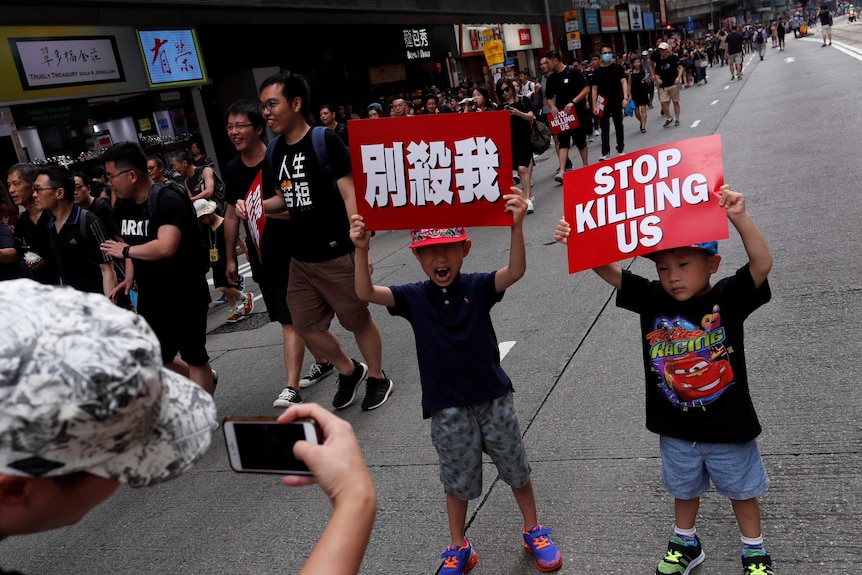 Children pose with placards that read "stop killing us" at a demonstration in Hong Kong.