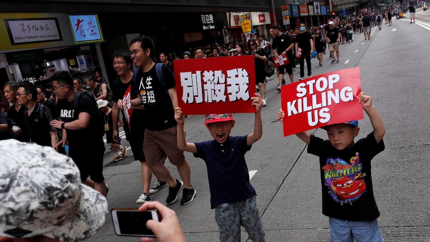 Children pose with placards that read "stop killing us" at a demonstration in Hong Kong.