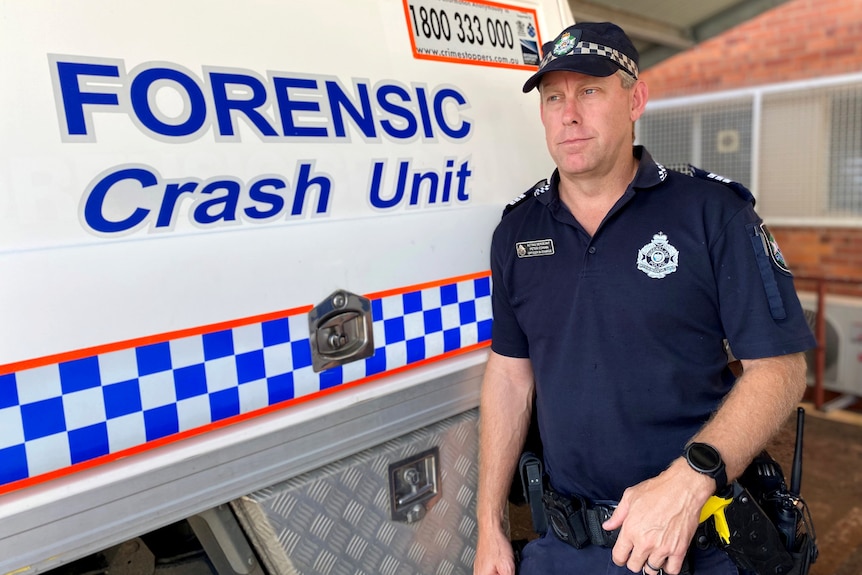 Police officer standing beside a police van that says forensic crash unit