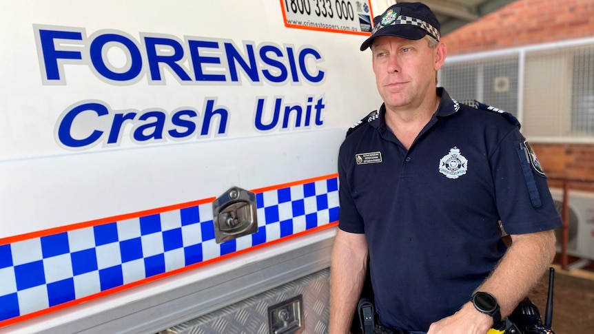 Police officer standing beside a police van that says forensic crash unit