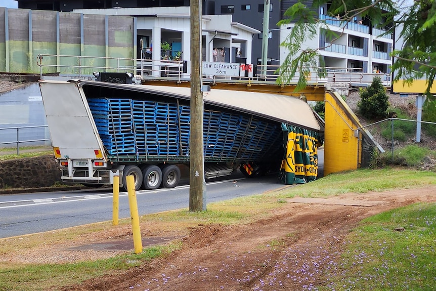 A truck stuck under a low rail bridge in Corinda