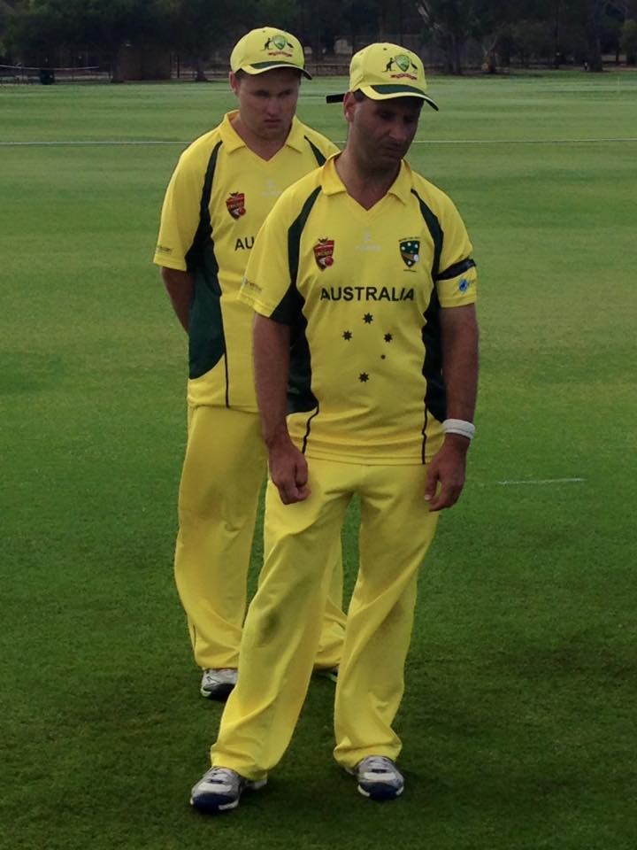 Two men standing in Australian cricket team uniforms on a cricket field