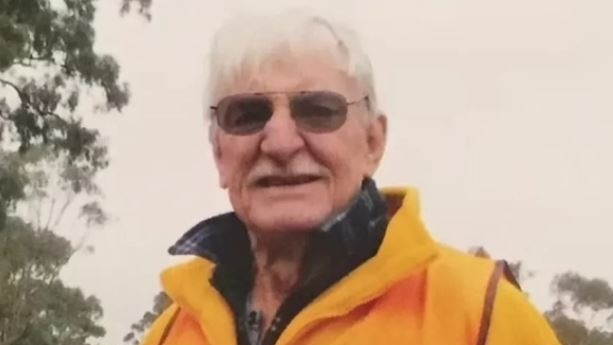 A man with white hair and a yellow jacket