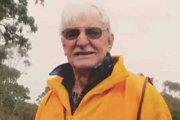 A man with white hair and a yellow jacket
