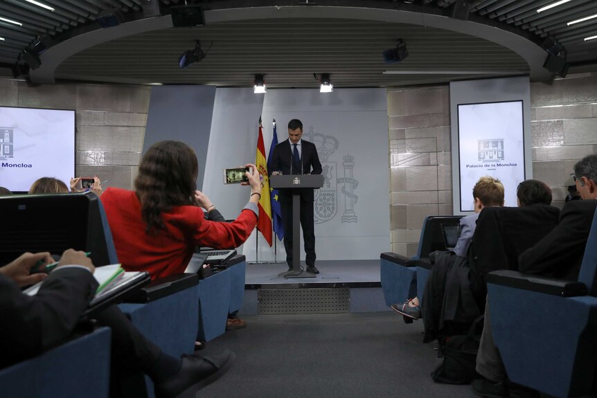 Spanish PM Pedro Sanchz is seen at a press conference photographed by female members of the audience.