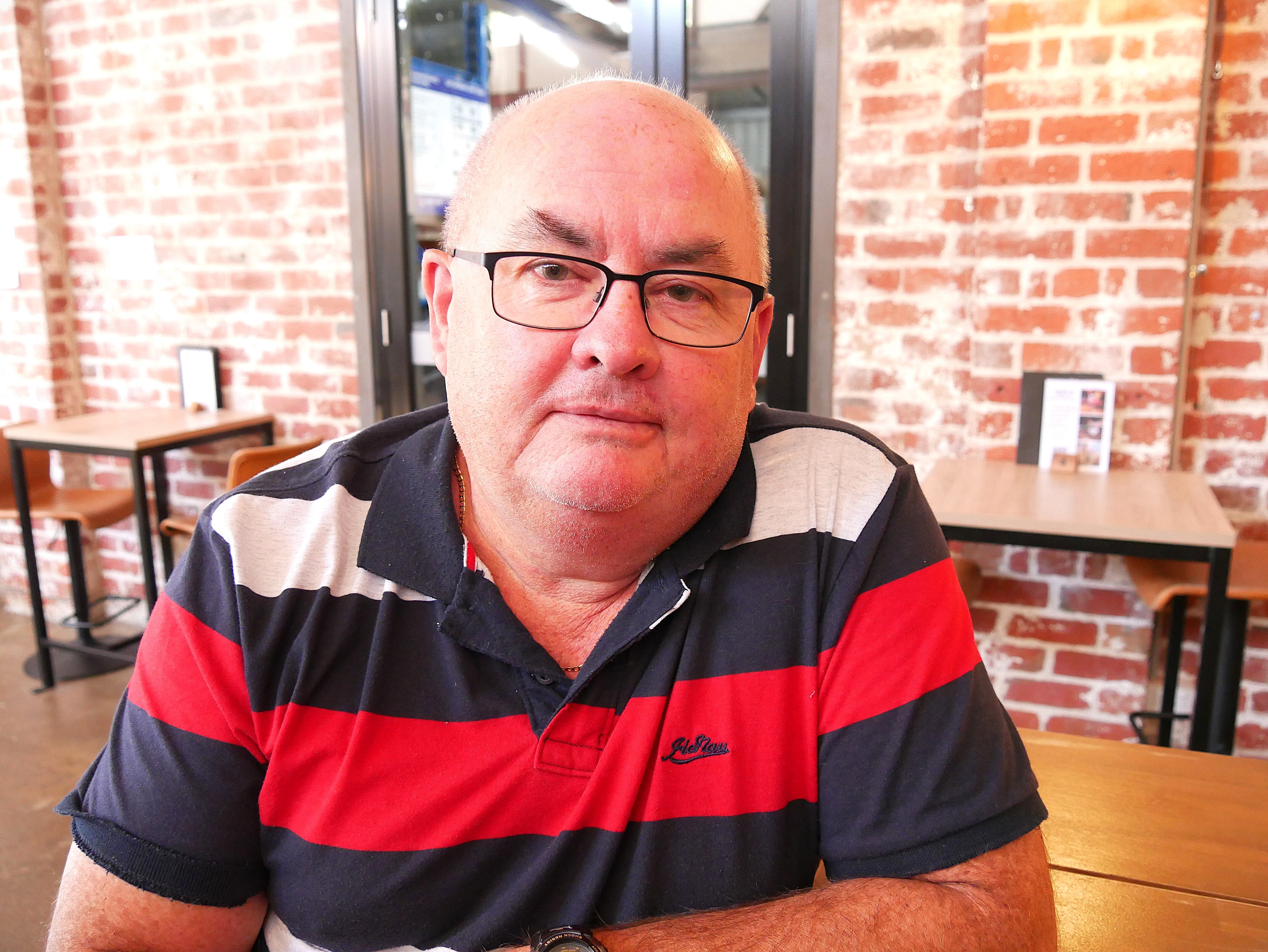 a man with glasses sitting staring at the camera.